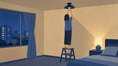 A person on a step stool holding a new bulb up to a dark ceiling light