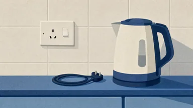 A wall socket switched off with a dark mark on the plate, a kettle cord coiled beside it